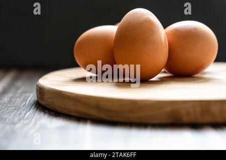 Three eggs on a rustic wooden tray with black background Stock Photo