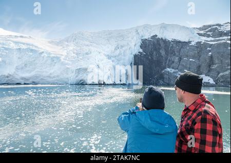 Tourists photographing falling Ice at Beloit Tidewater Glacier in Blackstone Bay, Prince William Sound, Alaska, USA Stock Photo