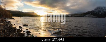 Scenic low level panorama of golden Sunset over Ume river with first ice, mountains covered by clouds. Lapland Sweden. Somewhere around Tarnaby villag Stock Photo