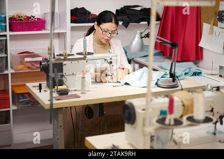 Young woman sews on a sewing machine Stock Photo