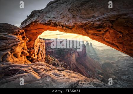 Mesa Arch, an icon of Canyonlands, frames the sunrise in its natural embrace, offering spectacular views through its majestic rock opening. Stock Photo