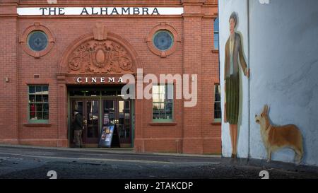 The Alhambra cinema Keswick and memorial mural of Queen Elizabeth II as a young woman with corgi in alleyway opposite, Keswick, Cumbria, England, UK Stock Photo