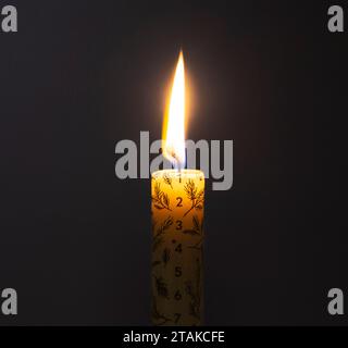 A lit Christmas advent candle on the first day of December against a black background Stock Photo