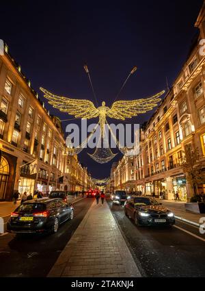 London, UK - Nov 20 2023: Regent Street in central London with traffic and Christmas lights overhead. People are Christmas shopping. Stock Photo