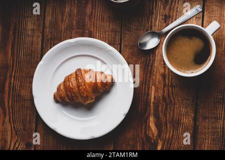 Fresh Croissant and Cup of Coffee on Wooden Surface. View from Above Stock Photo