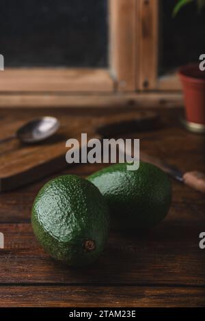 Two whole avocados with knife on rustic table Stock Photo