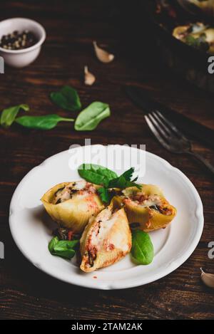 Baked jumbo shells pasta stuffed with ground beef, spinach and cheese on white plate Stock Photo