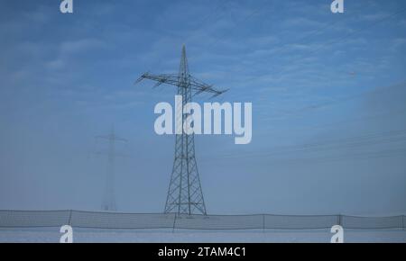 Winter 30.11.2023, Olbersleben, Strommasten auf einem Feld, Nebel steigt auf, Schneefangzaeune stehen am Strassenrand *** Winter 30 11 2023, Olbersleben, electricity pylons in a field, fog rising, snow fences at the roadside Credit: Imago/Alamy Live News Stock Photo