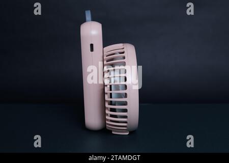 Mini electric pink pan, isolated on dark background. side view. Portable electrical equipment that very useful when hot weather. Stock Photo
