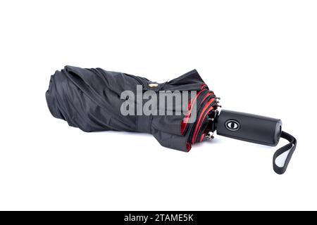 Folded umbrella with black top and red bottom on a white background. Copy space. Stock Photo