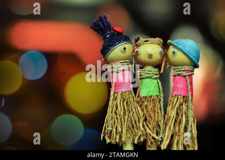 Three children's toy dolls made of wood and straw on a blurred background Stock Photo