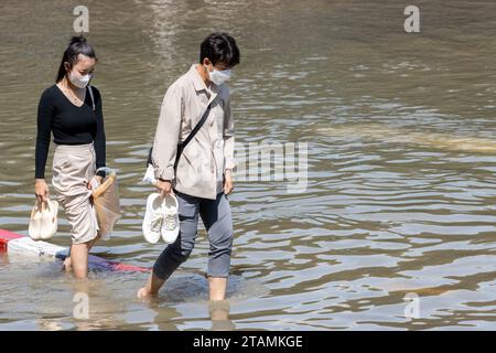 SAMUT PRAKAN, THAILAND, NOV 18 2023,  A couple wades through a flooded street Stock Photo