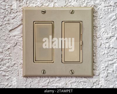 Dual wall rocker light switch with dimmer slider on a white wall Stock Photo