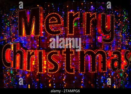 Merry Christmas word neon sign. Christmas lights in night city. Stock Photo