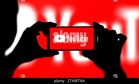 Youtube logo on smartphone with red background. Woman taking a photo or filming with mobile phone of youtube logo. Stock Photo