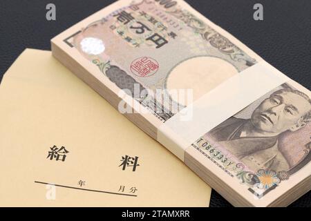 Japanese ten thousand yen on a salary bag on black background, Translation: salary, year, month, day. Stock Photo