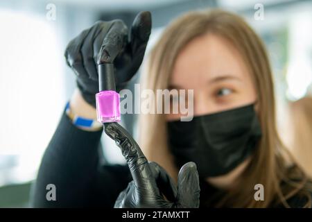 young woman getting her nails done by a manicurist in a beauty salon. a bottle of nail polish Stock Photo