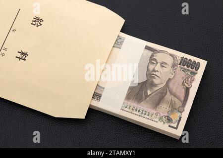 Japanese ten thousand yen on a salary bag on black background, Translation: salary, year, month, day. Stock Photo