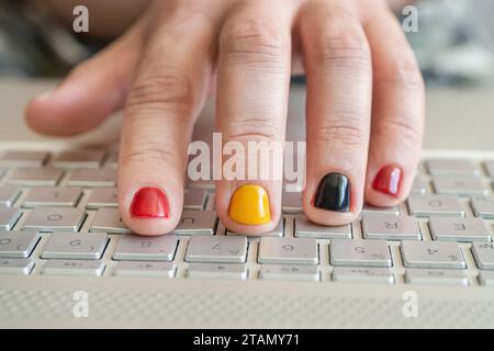 Hands on the laptop keyboard. A man with painted nails. Design of male nails. men manicure. Stock Photo