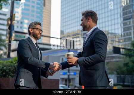 American businessman shaking hands with partner. Businessmen in suit shaking hands outdoors. Handshake between two businessmen. wo business men had Stock Photo