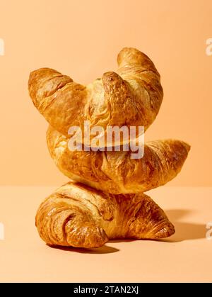 stack of freshly baked croissants on orange color background Stock Photo