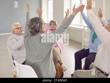 Senior people talking on therapy session at nursing home holding hands up together. Stock Photo