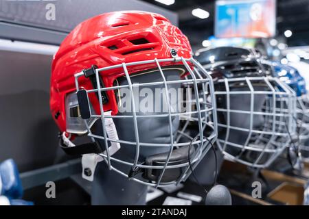 Two vibrant hockey helmets, one blue and one red, with clear visors, displayed in an organized manner on a shelf, ready for players to gear up and hit Stock Photo
