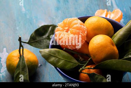 Fresh juicy tangerines in a blue ceramic bowl on wooden background. Stock Photo