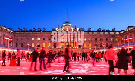 At the Somerset House SKATE ice rink, skaters enjoy a round on the ice in front of the beautifully illuminated building. On a clear but very cold 1st December, festive lights and decorations illuminate many central London areas busy with tourists, visitors and Londoners enjoying their evening. Stock Photo
