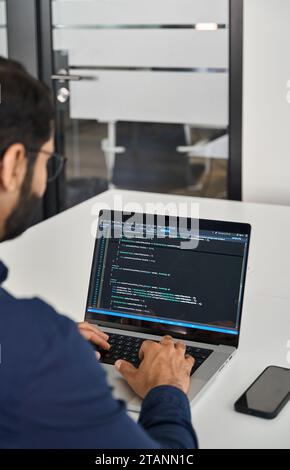 Busy businessman software developer working on computer in office. Over shoulder Stock Photo