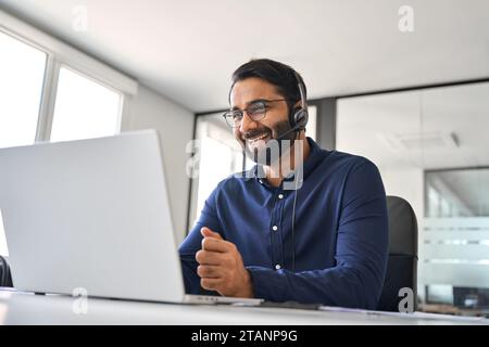 Smiling Indian call center agent in headset working in customer support office. Stock Photo
