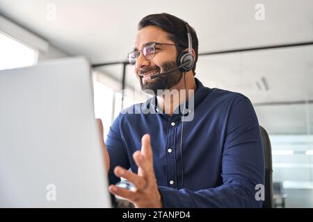 Smiling Indian call center agent in headset working in customer support office. Stock Photo
