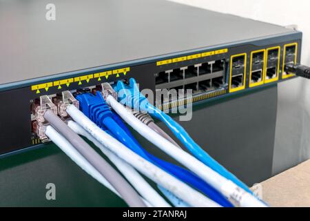 Network Gigabit Smart PoE Switch with  connected network cables getting tested on the desk Stock Photo