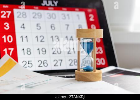 Time passing concept, time slipping away. Hourglass and the calendar Stock Photo