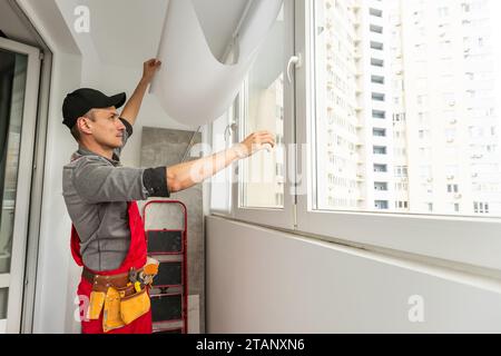 handsome repairman in goggles measuring wall near window  Stock Photo