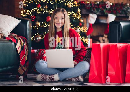 Full body photo of teen girl with netbook browsing internet looking for gifts black friday offers isolated on pine tree background indoors Stock Photo