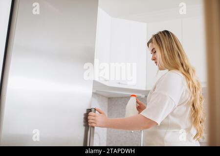 Young woman taking gallon of milk from refrigerator in kitchen. Stock Photo