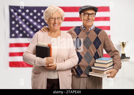 Elderly man and woman holding books and posing in front of an american flag Stock Photo