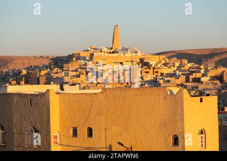 view of city with mud-brick dwelling and tall minaret against clear sky, Algeria, Ghardaia, Africa Stock Photo