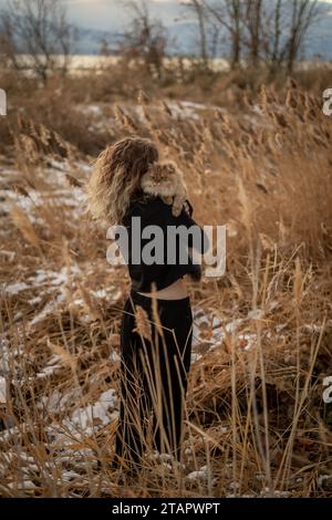 Female Curly Haired Person with Fluffy Kitty Hugging Outside Portrait Cloudy Black Clothes Kissing Cat Stock Photo