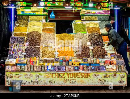 Marrakech, Morocco, April 8th, 2023. A Moroccan male vendor preparing the food at a colourful dried fruits stall in Marrakech Jemaa el-Fnaa Square. Stock Photo