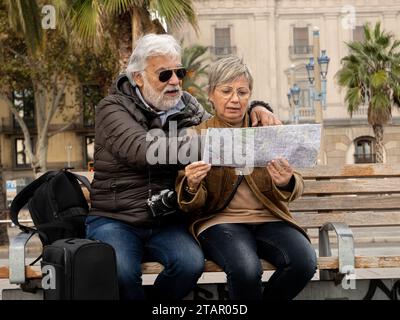 Middle aged heterosexual couple tourists looking at a map in a city during vacation Stock Photo