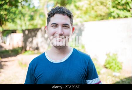Portrait of Latin American man looking and smiling at the camera. Portrait of cheerful young latin guy smiling at camera outdoors Stock Photo