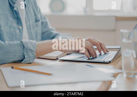 Close-up of a man's hands typing on a laptop keyboard, concept of remote work Stock Photo