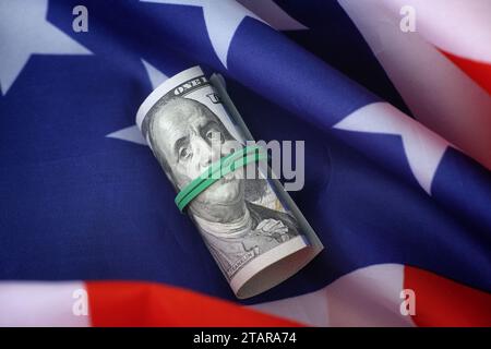 A one hundred dollar bill lying on an American flag. Close up. Stock Photo
