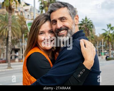 Portrait of a middle aged heterosexual couple embracing looking at camera in a city Stock Photo