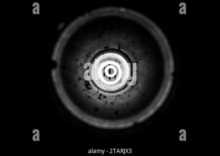 Flashlight light in an empty used anti-tank grenade launcher as a background, bright light in a circle, light from a hole, black and white photo Stock Photo