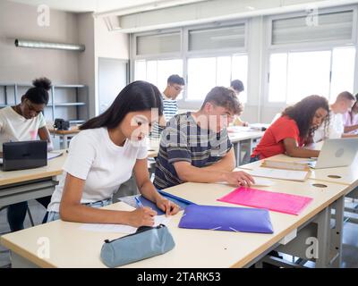 Group of diverse teenage students taking an exam in a class. Education day concept Stock Photo