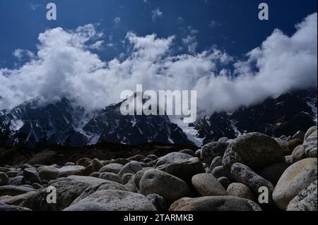 This image is a stunning landscape of nature, featuring mountains, rock. Majestic mountains in the background. The sky  is filled with fluffy clouds Stock Photo