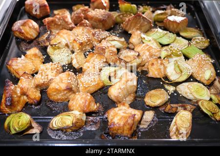 Cubes of teriyaki salmon covered in sesame seeds on oven pan coming out of air fryer Stock Photo